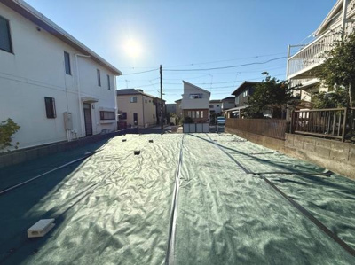 陽当たりの良い現地土地写真です。周囲には住宅が並び落ち着いた雰囲気が感じられます。整地されており即利用できる状態です。前面道路との高低差も少なくアクセスがしやすい印象です。