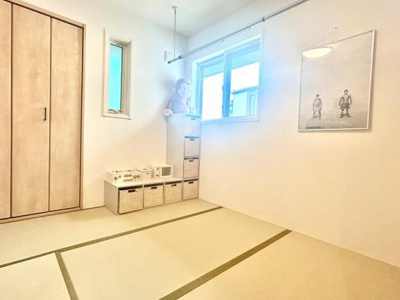 明るい光が差し込む和室です。シンプルな内装で収納スペースも充実しています。窓が二つあり換気や採光に配慮されています。壁にアートが飾られているのが印象的です。床は畳敷きとなっております。