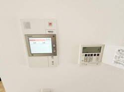カラーモニター付きのインターホンを設置しています。室内から来訪者を確認できるシステムです。隣には便利な給湯操作パネルも配置されています。壁面はシンプルで清潔感があります。