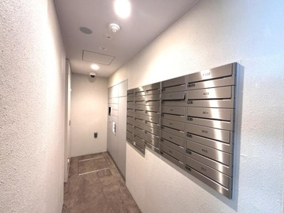 壁面に設置されたメールボックスが整然と並んでおりエントランスの印象を引き締めます。清潔感のある明るい通路で使いやすい設計です。照明がしっかり配置され安心感があります。共用部の手入れも行き届いています。