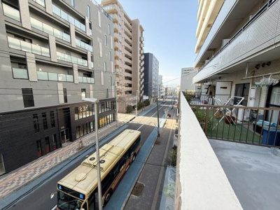 現地からの眺望では前面に開けた街並みが広がっています。バス通りに面しているため利便性も感じられます。周囲には高層マンションが立ち並び都市的な景観が楽しめます。バルコニーからの見通しも良好です。