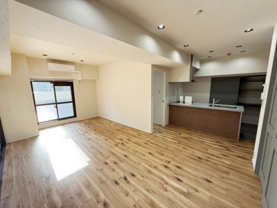 広々としたリビングは木目調のフローリングが温かみを感じさせます。キッチンとの一体感があり開放的な空間です。天井のダウンライトと大きな窓が室内に明るさをもたらします。