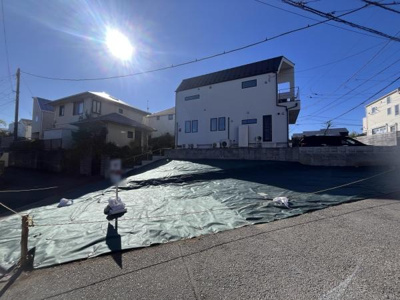 陽射しがたっぷりと差し込む現地写真です。前面道路が広々としており車の出入りもスムーズです。周囲には落ち着いた住宅が並び開放感のある立地です。現地の様子がはっきりとわかる一枚です。