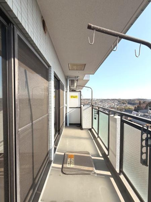 広々としたバルコニーで複数の物干し金具が設置されています。眺望も開放感があり外の景色が遠くまで見渡せます。ガラスパネルの手すりがスタイリッシュな印象です。日当たりの良さを感じる空間です。