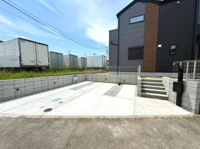 コンクリート舗装が施された駐車場です。ゆとりのあるスペースで複数台の駐車が可能です。段差の少ない設計で車の出し入れもスムーズに行えます。横には階段もあり建物へのアクセスも便利です。