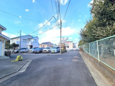 前面道路は広々とした印象で周辺には住宅や駐車スペースが整然と並んでいます。道路沿いにはフェンスや植栽があり落ち着いた街並みが広がっています。視界も開けているため車両の出入りがしやすそうです。