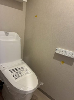 温水洗浄機能付きのトイレです。明るく清潔感があり、白を基調とした内装で空間が広く感じられます。壁面上部には清掃用具を収納できるスペースを設けております。