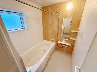 明るい木目調の壁がアクセントになったバスルームです。浴槽はゆったりとしたサイズ感で使いやすい設計です。小窓があり換気や採光も確保されています。シンプルで清潔感のある空間です。