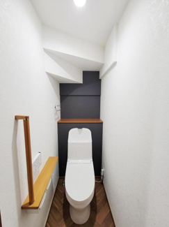 コンパクトながらも清潔感のあるトイレです。落ち着いた色合いの壁が空間にアクセントを加えています。手すりが設置されており使いやすさにも配慮されています。照明が明るく快適にご利用いただけます。