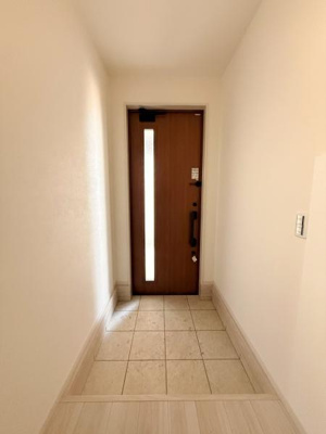 玄関には縦長のスリット窓があり自然光が差し込む明るい印象です。タイル張りの床でお手入れもしやすそうです。シンプルなデザインで空間がすっきりとしています。清潔感があり使いやすい玄関です。