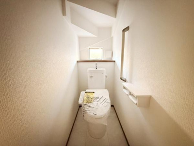 明るい光が差し込むトイレです。シンプルなデザインで清潔感があります。収納スペースも確保しやすい配置です。上部には開放感のある窓が設けられ空間に奥行きを感じられます。