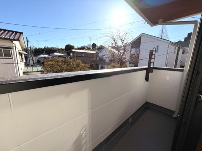 日当たりの良いバルコニーで空が広く開放感があります。周囲には住宅が並び落ち着いた雰囲気が漂います。高めの手すりで安心感もあります。使いやすいスペースが広がっています。快適なバルコニー空間です。