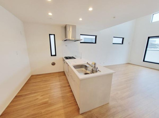 シンプルなデザインのキッチンが室内全体をすっきりとした印象にしています。明るい床材と白い壁が空間を広く見せてくれます。複数の窓が取り入れる自然光でキッチンエリアが快適です。