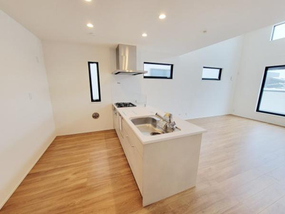 シンプルなデザインのキッチンが室内全体をすっきりとした印象にしています。明るい床材と白い壁が空間を広く見せてくれます。複数の窓が取り入れる自然光でキッチンエリアが快適です。