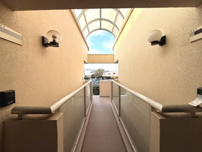 クリアなガラス手すりとアーチ型の屋根が開放感を演出しています。照明も設置されており夜間も安心してご利用いただけます。明るい通路で快適に移動できます。空の景色も楽しめるスペースです。