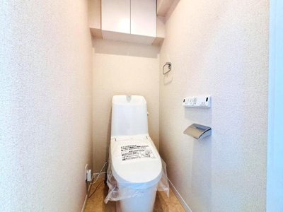 すっきりとした空間のトイレです。収納棚が設置されており整理整頓に便利です。壁側にはペーパーホルダーと操作パネルが配置されています。シンプルなデザインが特徴です。清潔感のある内装です。