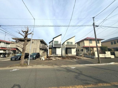 ゆったりとした前面道路が特徴で車の出し入れも安心です。建物の個性的な外観が印象的な現地写真です。周囲には落ち着いた住宅が並び開放感のある街並みが広がっています。