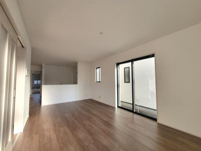 南向きの大きな窓から明るい光が差し込むリビングです。広々とした空間は自由なレイアウトを楽しめます。木目調のフローリングが落ち着いた雰囲気を演出しています。隣接したキッチンとの繋がりも良好です。