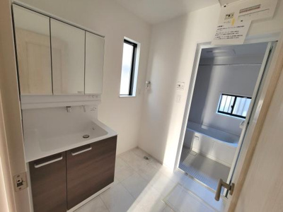 清潔感のある洗面台で三面鏡付きの収納スペースが特徴です。明るい採光があり床もメンテナンスしやすい素材を使用しています。洗面所から浴室へのスムーズな導線も魅力です。