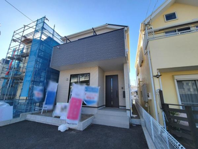 現代的なデザインが印象的な建物外観です。落ち着いた色合いの外壁が周囲と調和しています。玄関へのアプローチも明るく開放的です。