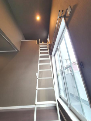 天井が高く開放感のある空間です。ロフトへアクセスできるはしご付きで収納やスペースの活用に便利です。大きな窓から自然光が入り室内が明るい印象です。シンプルな内装が特徴的です。