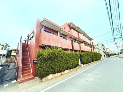 赤レンガ調の外観が印象的な建物です。前面道路は幅が広く車の出し入れがしやすそうです。緑の植栽が建物を囲み落ち着いた雰囲気を感じられます。角地に位置しており開放感もあります。