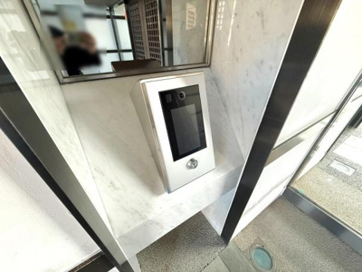 エントランスに設置されたモニター付きインターホンが来訪者の確認をサポートします。スタイリッシュなデザインが空間に調和しています。パネル操作も分かりやすい仕様です。清潔感のある壁面仕上げが印象的です。