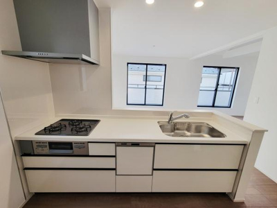 シンプルな配色でまとめられたキッチンです。広々としたワークトップが確保されています。窓からの採光により明るい印象が広がります。収納スペースも確保されていて整理しやすい設計です。