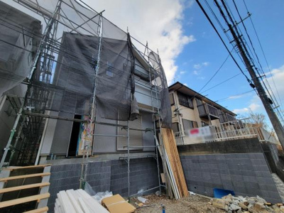 建物の外観がしっかりと確認できる写真です。工事の進捗状況が分かりやすく周囲の環境も映っています。足場や資材が整然と配置されており現場の様子が伝わります。道路や隣接する住宅との位置関係も見て取れます。