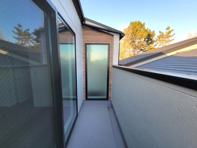 落ち着いた色合いの外壁と窓ガラスが調和するバルコニーです。屋根付きのため天候の変化にも対応しやすい仕様です。周囲の景色を楽しめる開放的な雰囲気です。プライバシーに配慮した壁の高さも安心感があります。