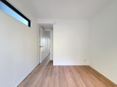 シンプルで明るい内装が魅力の洋室です。ナチュラルなフローリングが空間に調和しています。壁面にはコンセントも設置されています。天井近くの窓が採光に配慮されています。動線も使いやすいレイアウトです。