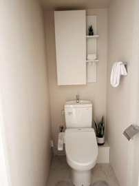 収納スペースが設けられたトイレとなっています。コンパクトながらも清潔感のある内装です。観葉植物がアクセントとなり落ち着いた雰囲気を演出しています。手洗い器付きのタンクで便利に使えます。