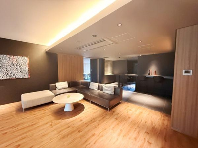 落ち着いた色合いの壁と床が調和するリビングスペースです。広々とした空間にモダンなソファが設置され開放感を感じられます。天井に設置された照明が柔らかく明るさを確保しています。