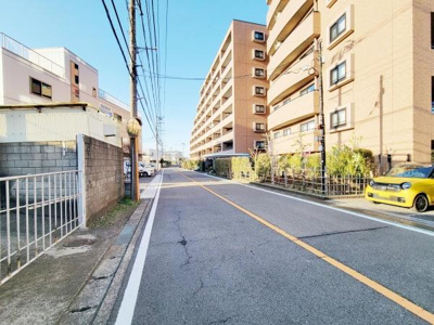前面道路は広く車の通行にも安心感があります。道路沿いには植栽が整備されており周囲の建物もバランスよく配置されています。