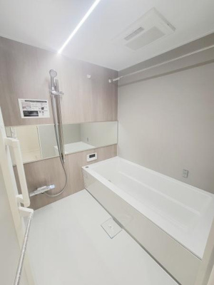 明るく清潔感のあるバスルームです。大きな鏡が空間を広く見せています。浴槽・シャワーともに使いやすい配置です。白を基調とした内装で印象的です。空調設備も備わっています。