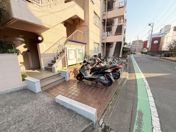 建物エントランス横にはバイクや自転車の駐輪スペースがあります。歩道に面した立地で移動にも便利です。入口部分は段差が低めで出入りしやすくなっています。