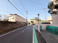 道路幅が広めで車両の通行や駐車もスムーズです。周囲には住宅や施設が点在し落ち着いた街並みが感じられます。道路脇には緑色ラインが施されており歩行者の安全にも配慮された設計です。