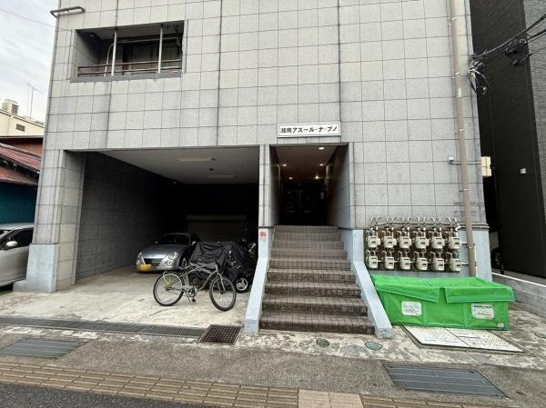 建物外観はシンプルなデザインで落ち着いた雰囲気が感じられます。入口前には駐輪スペースと駐車スペースが設けられており生活利便性が高い構造です。複数のガスメーターが整然と配置されているのも特徴的です。