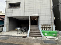 建物外観はシンプルなデザインで落ち着いた雰囲気が感じられます。入口前には駐輪スペースと駐車スペースが設けられており生活利便性が高い構造です。複数のガスメーターが整然と配置されているのも特徴的です。