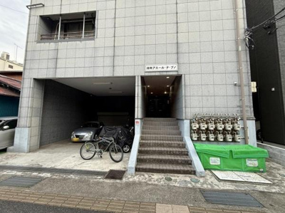 建物外観はシンプルなデザインで落ち着いた雰囲気が感じられます。入口前には駐輪スペースと駐車スペースが設けられており生活利便性が高い構造です。複数のガスメーターが整然と配置されているのも特徴的です。