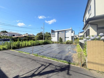 敷地は整然とした状態で管理されています。前面道路は幅員が十分あり車両の出入りに適しています。晴れた日の撮影で周囲の住宅街の様子が分かりやすい写真です。周辺は戸建ての並ぶ落ち着いた街並みです。