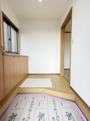 玄関は明るく木目調の収納が設置されています。窓からの採光で爽やかな空間になっています。シンプルな設計で日々使いやすい印象です。室内との段差も控えめに作られています。