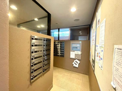 明るいエントランスで訪問者を温かく迎えます。しっかりとした郵便受けが備わっており便利です。落ち着いた色合いの壁が洗練された印象を与えます。