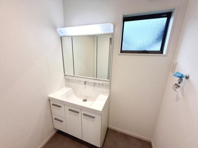 洗面台・洗面所は明るく清潔感のある空間です。大きな三面鏡が備わっており収納スペースもしっかり確保されています。窓があることで自然光が入り換気も良好です。シンプルなデザインが使いやすさを感じさせます。