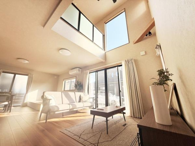 吹き抜けから差し込む自然光がリビング全体を明るく包みます。広々とした空間が開放感を演出しています。大きな窓が外の景色を取り込み室内をより一層快適にします。