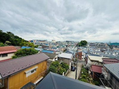 周囲の住宅街を一望できる眺めが広がっています。見晴らしの良さが印象的です。日々の空模様や町並みを身近に感じられます。屋根や道が連なり奥行きを感じる現地からの眺望です。静かな環境が伝わる風景です。