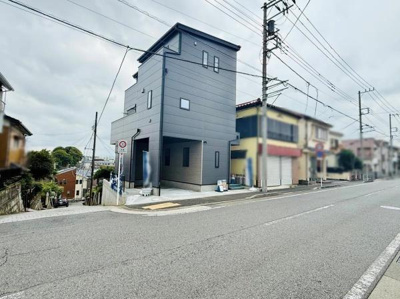 前面道路が広く車の出入りがしやすい立地です。現地写真から周囲の街並みが確認できます。建物の外観はシンプルで落ち着いた印象です。周辺は住宅や店舗が立ち並ぶエリアとなっています。