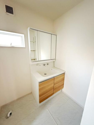 明るい空間が広がる洗面所です。大型のミラーキャビネットが備わり日々の使い勝手に配慮されています。シンプルなデザインと木目調のキャビネットが調和しています。清潔感のある床材でお手入れしやすい仕様です。
