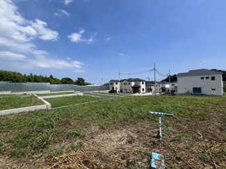 広い空の下ゆとりある空間が広がる現地土地写真です。周囲に新しい住宅が並び開放的な印象を与えます。整然とした区画で落ち着いた住環境を感じることができます。緑も多く周囲との調和が取れています。