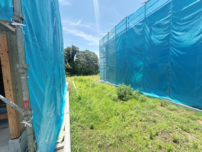 開放感のある土地で自然光がしっかりと差し込む環境です。周囲には緑が広がり落ち着いた雰囲気が感じられます。整った地形で建築計画も立てやすい現地土地写真です。青空と周辺の木々が印象的な一枚となっています。